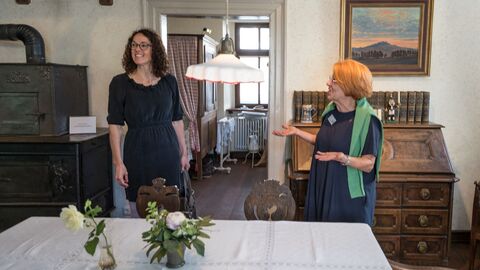 Ministerin Dorn mit Rosemarie Töpelmann, der Leiterin des Heimatmuseums Reinheim Ministerin Dorn steht mit Museumsleiterin Rosemarie Töpelmann im Reinheimer Heimatmuseum in einer historisch gestalteten Stube mit Kachelofen