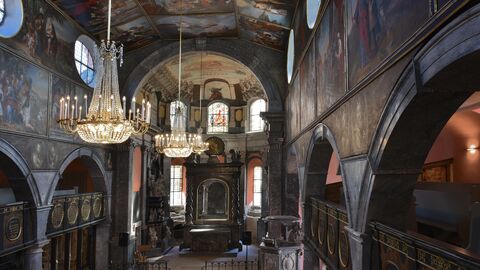 Blick in die gotische Unionskirche mit Kronleuchtern, Bibelszenen an den Wänden und hölzernem Kirchengestühl