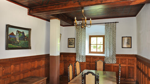 Blick in die Wohnstube der Wasserburg; man sieht historische Möbel wie Truhe, Tisch und Stühle