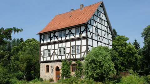 Die Wasserburg von außen, ein mehrstöckiges Fachwerkhaus mit rotem Dach