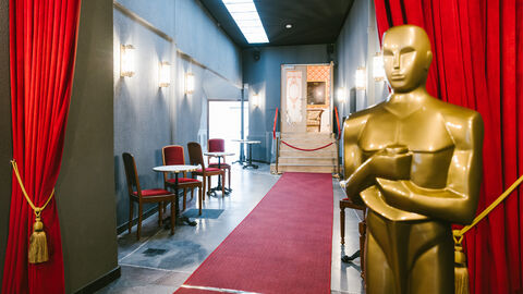 Eingang der FilmBühne in Bad Nauheim, man sieht einen Gang mit rotem Teppich, lebensgroßer Oscar-Statue und roten Vorhängen