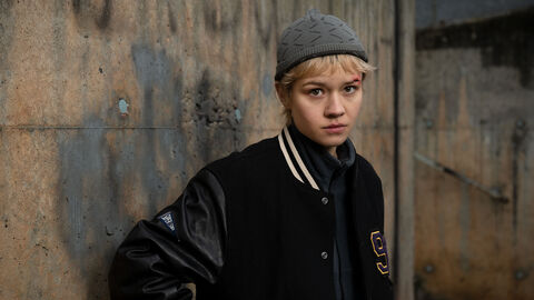 Szene aus "Becoming Charlie": Lea Drinda steht vor einer Wand und blickt herausfordernd in die Kamera