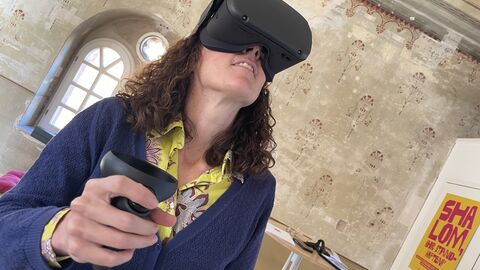 Ministerin Dorn trägt eine VR-Brille und bewegt sich damit in der ehemaligen Synagoge Abterode