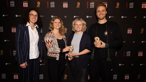 Kunst- und Kulturmiinisterin Angela Dorn steht mit den Preisträgerinnen und Preisträgenr Hochschulabschlussfilm und Kurzfilm vor einer Wand mit Logos.