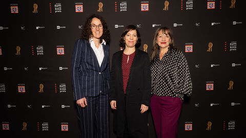 Ministerin Angela Dorn steht mit Julia Irene Peters und Jutta Feit, Trägerinnen des Newcomerpreises 2022, vor einer Fotowand.