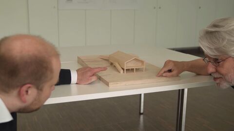 Zwei Professoren sehen sich ein kleines Modellhaus an.