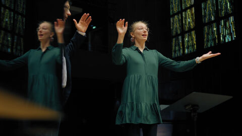 Eine Dirigentin hebt die Arme