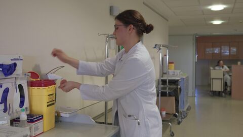 Eine Studentin im weißen Kittel desinfiziert sich im Krankenhaus die Hände.