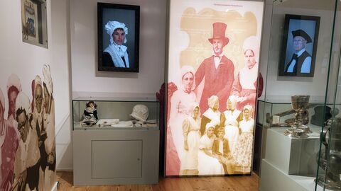 Das Philipp-Reis-Haus beleuchtet auch die Geschichte der Hugenotten in Friedrichsdorf und Umgebung. Blick in die Ausstellung des Philipp-Reis-Hauses: Gemälde an den Wänden, Kleidungsstücke in den Vitrinen