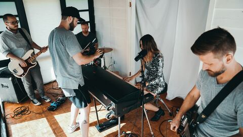 Eine vierköpfige Band spielt, ein Mann filmt sie mit der Kamera