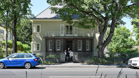 Ministerin Dorn steht mit dem Eigentümer-Ehepaar vor der Doppelvilla in Darmstadt.