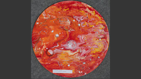 Eine rote Scheibe mit Mustern und eingeritzten Motiven wie Planeten und Gesichtern