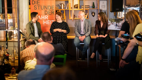 Ministerin Dorn sitzt mit ihren Gästen und Moderator Tim Berendonk in einer Gesprächsrunde, um sie herum das Publikum.