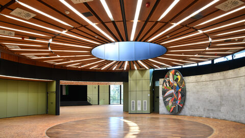 Die Hattersheimer Stadthalle hat den Hessischen Denkmalschutzpreis 2023 in der Kategorie "Öffentliches Bauen" gewonnen. Blick in die Hattersheimer Stadthalle mit runder Holzpaneelenanordnung und Glaskuppel