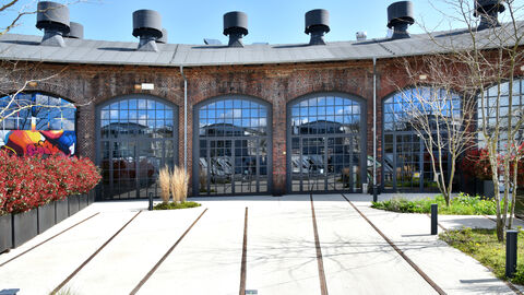 Heute ist der Lokschuppen ein Veranstaltungszentrum, in dem neue Bauteile mit historischer Substanz harmonieren.  Der umgebaute Lokschuppen mit großen Fensterfronten.