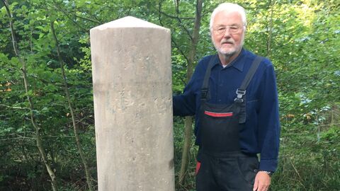 Dr. Wilhelm Ott dokumentiert historische Grenzsteine im Landkreis Offenbach. Dr. Wilhelm Ott steht neben einem Grenzstein.