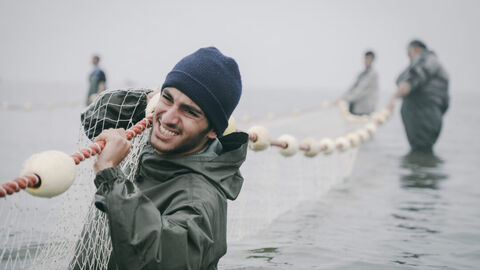 Szene aus "Leere Netze" Szene aus "Leere Netze": Männer schleppen ein Netz durchs Wasser