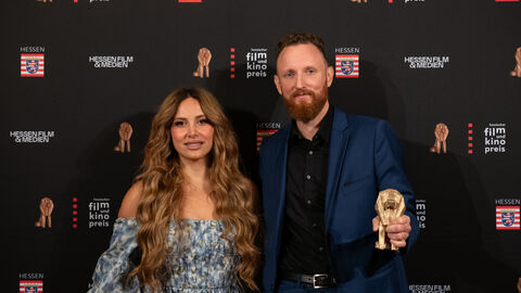Julian Vogel, Gewinner der Kategorie "Bester Dokumentarfilm", mit Laudatorin Enissa Amani vor der Fotowand