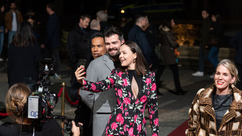 Personen machen Selfies auf dem roten Teppich.