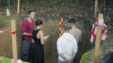 Bei Dr. Vincent Feldes Lehrprojekt sammeln die Studierenden praktische Erfahrungen bei der Bodenanalyse im Gelände.  Dr. Vincent Felde steht mit Studierenden in einer Baugrube im Wald und untersucht Bodenproben.