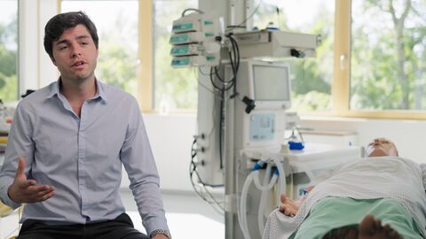 Die Studierenden Philipp Kremer und Leonard Richter analysieren im Online-Seminar Patienfälle aus der Praxis. Leonhard Richter sitzt neben einer medizinischen Puppe.