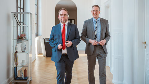 Wissenschafts- und Kunstminister Timon Gremmels (links) und Staatssekretär Christoph Degen bilden die neue Hausspitze im HMWK. Timon Gremmels und Christoph Degen laufen auf die Kamera zu.