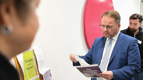 Minister Gremmels schaut sich Material zum wissenschaftlichen Schreiben an.