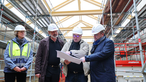 Minister Gremmels schaut sich einen Plan auf der Baustelle an.