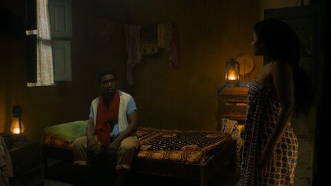 Szene aus "Tug War" Szene aus "Tug War": Ein schwarzer Mann und eine schwarze Frau in einem Zimmer. Er sitzt auf dem Bett, sie steht ihm gegenüber.