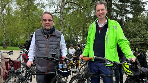 Minister Gremmels und OB Schoeller stehen mit Fahrrädern in der Karlsaue am neuen Radweg.