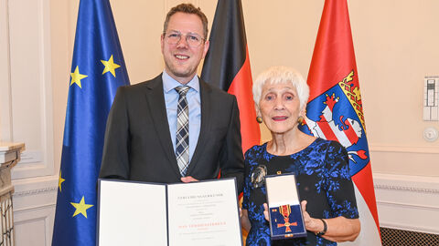 Staatssekretär Christoph Degen überreicht Christa Leiendecker das Bundesverdienstkreuz.