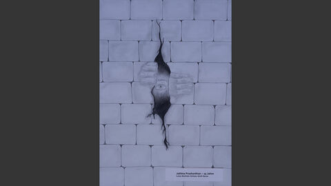 Eine Backsteinmauer, durch die ein Riss geht. Dahinter sieht man eine Person, die die Steine mit den Händen auseinanderschiebt.