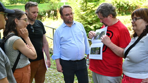 Impressionen vom Besuch im UNESCO-Welterbe Bergpark Wilhelmshöhe. Minister Gremmels umringt von Menschen, er lässt sich etwas auf einer Karte zeigen.