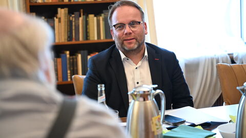 Impressionen vom Sommerreise-Besuch in der Phantastischen Bibliothek Wetzlar. Minister Gremmels im Gespräch am Tisch mit Mitarbeitenden der Bibliothek.