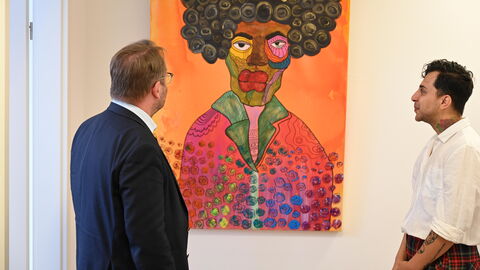 Impressionen vom Sommerreise-Besuch im Refugee Counseling Center und in der Kunstausstellung von Atish Shahbazi. Minister Gremmels und der Künstler Atish Shahbazi schauen sich ein Gemälde an