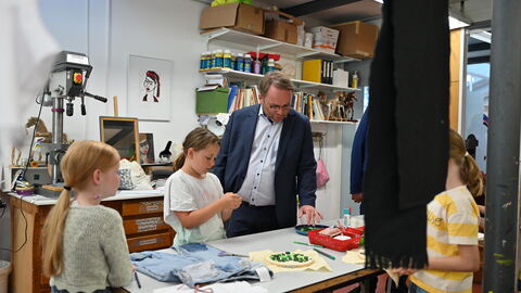 Impressionen vom Sommerreise-Besuch in der Kinder-Akademie Fulda. Minister Gremmels schaut zu, wie Kinder basteln