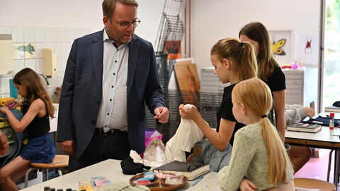 Impressionen vom Sommerreise-Besuch in der Kinder-Akademie Fulda. Minister Gremmels schaut zu, wie Kinder basteln