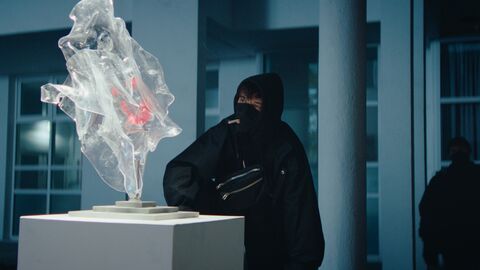 Szene aus "Kûnstscheissé" Szene aus "Kûnstscheissé": Ein vermummter Mann steht vor einer Plastik
