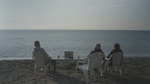 Szene aus "Exile never ends": Menschen sitzen am Strand