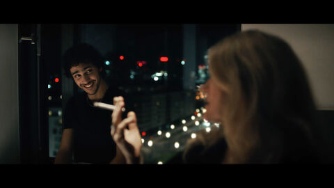 Szene aus "Klandestin" Eine Frau raucht, ein Mann lächelt sie dabei an