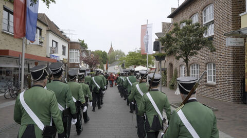 Szene aus "Die Stadt ist die Gilde und die Gilde ist die Stadt" Szene aus "Die Stadt ist die Gilde und die Gilde ist die Stadt": Männer in Schützenvereinsuniformen marschieren durch die Straßen