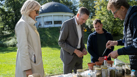 Staatsssekretär Degen beobachtet, wie ein Mann mit einer Pipette Gläser mit verschiedenen Böden behandelt