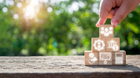 Eine Hand baut Würfel mit Symbolen aufeinander, die für verschiedene Jobvorteile stehen