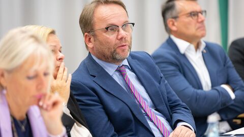 Timon Gremmels sitzt an einem Tisch und hört gespannt zu.