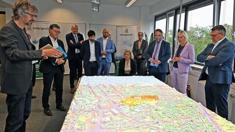 Männer und Frauen stehen um einen Tisch, der die Miniaturansicht einer Stadt zeigt.