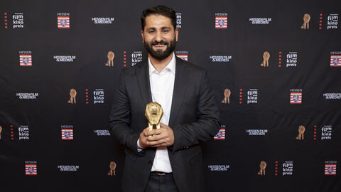 Nur Muhammed Tarhan Nur Muhammed Tarhan vor einer Fotowand