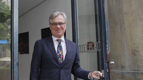 Jürgen Braasch  Ein Mann hat eine Tür geöffnet und hält die Türklinke noch in der Hand während er in die Kamera lächelt.