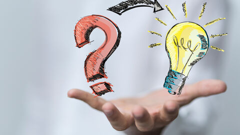 Eine Hand balanciert ein Fragezeichen und eine Glühbirne