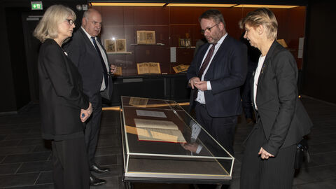 Minister Gremmels schaut sich wertvolle Dokumente in der Bibliothek an.
