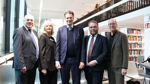 Thomas Platte (Direktor des Landesbetriebes Bau und Immobilien Hessen), Claudia Martin-Konle (Ltd. Bibliotheksdirektorin UB Kassel), Dr. Sven Schoeller (Oberbürgermeister der Stadt Kassel), Timon Gremmels (Hessischer Minister für Wissenschaft und Forschung, Kunst und Kultur) und Dr. Oliver Fromm (Kanzler der Universität Kassel)  stehen in der Bibliothek